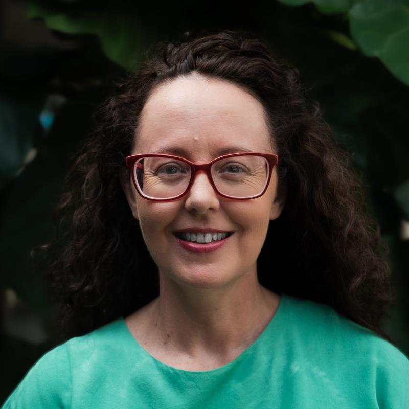 Lady in red glasses wearing a green t-shirt. 